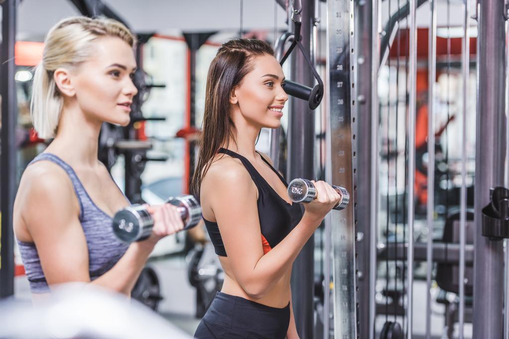 mujeres deportivas sonrientes haciendo ejercicio con pesas en el gimnasio
 - Foto, Imagen