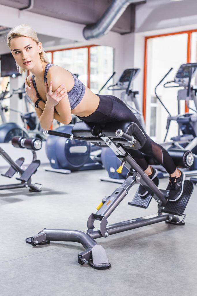 jonge sportieve vrouw doen Hyperextensie oefening op gym machine - Foto, afbeelding