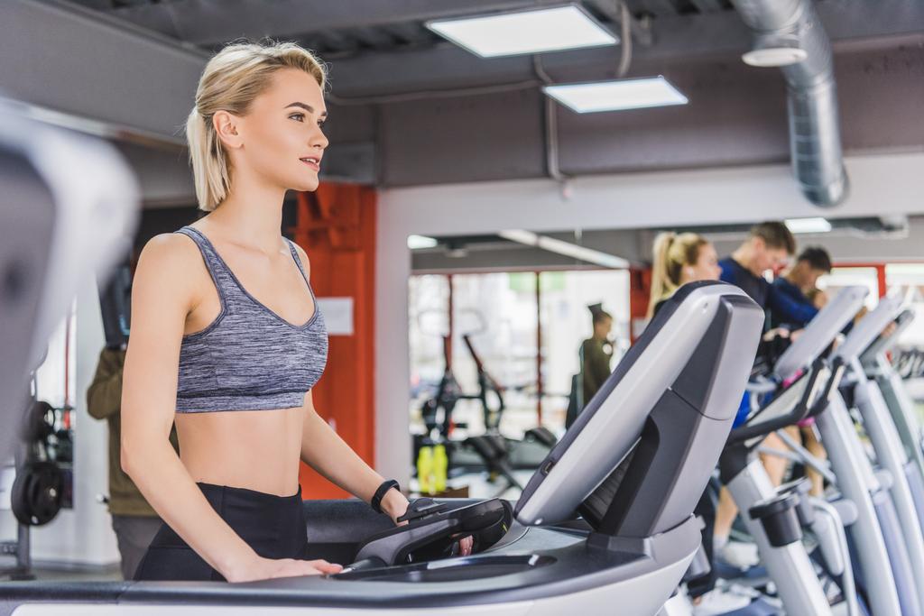 sportive young woman running on treadmill at gym - Photo, Image