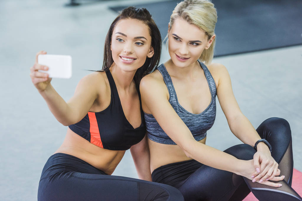 mujeres deportivas felices tomando selfie en el gimnasio
 - Foto, imagen