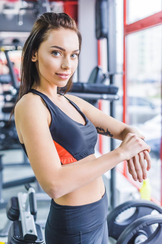 jovem mulher esportiva verificando rastreador de fitness no ginásio e olhando para a câmera
 - Foto, Imagem