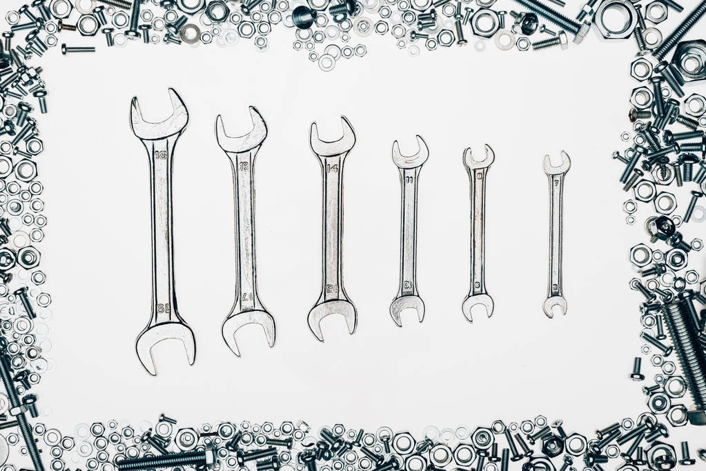 bovenaanzicht van metalen slagmoersleutels, diverse bouten en framing nagels geïsoleerd op wit - Foto, afbeelding