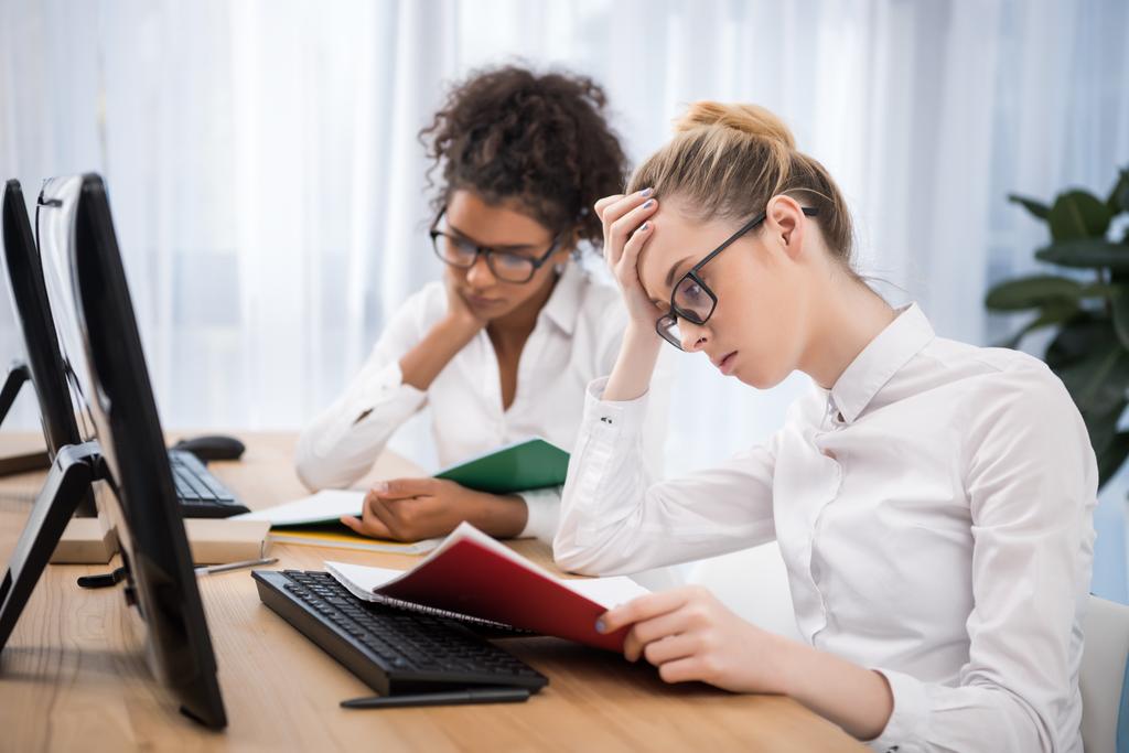 jeunes adolescentes fatiguées étudiant sur des ordinateurs avec des cahiers d'exercices
 - Photo, image