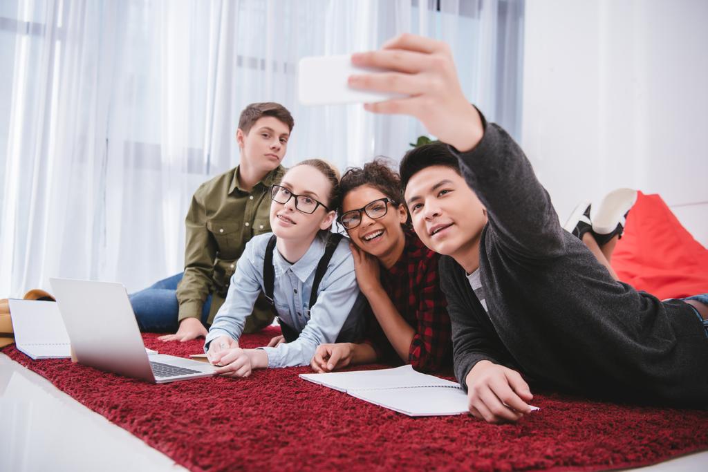 jonge tiener studenten liggen op tapijt en nemen selfie - Foto, afbeelding