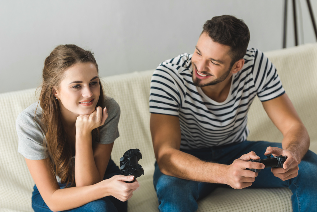 beautiful young couple playing games with gamepads at home - Photo, Image
