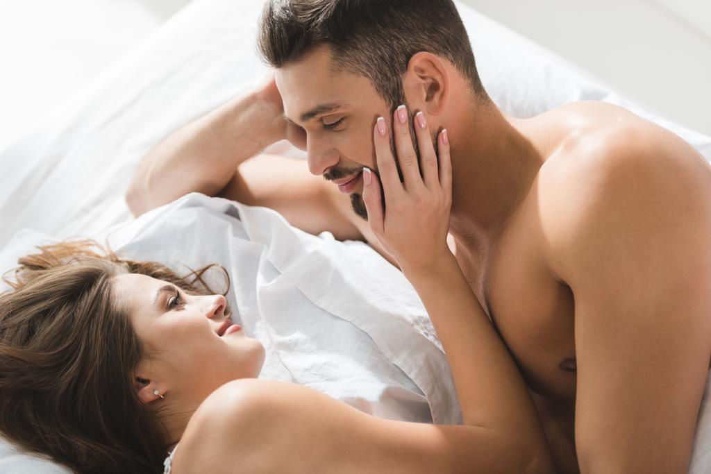vista de ángulo alto de la joven pareja relajándose juntos en la cama por la mañana
 - Foto, imagen