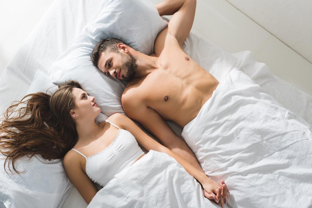 вид зверху молода пара тримає руки в ліжку вранці
 - Фото, зображення