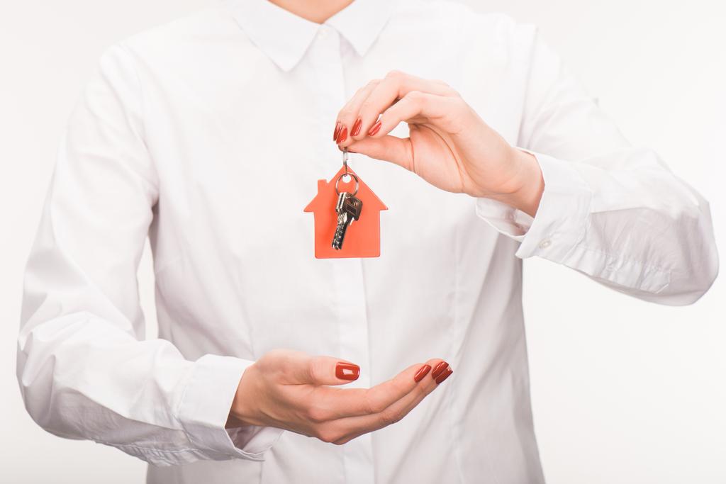 περικομμένη εικόνα του θηλυκού κρατώντας το κλειδί από το σπίτι που απομονώνονται σε λευκό - Φωτογραφία, εικόνα