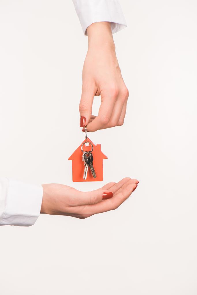 abgeschnittenes Bild weiblicher Hände mit Schlüssel aus Haus isoliert auf Weiß - Foto, Bild