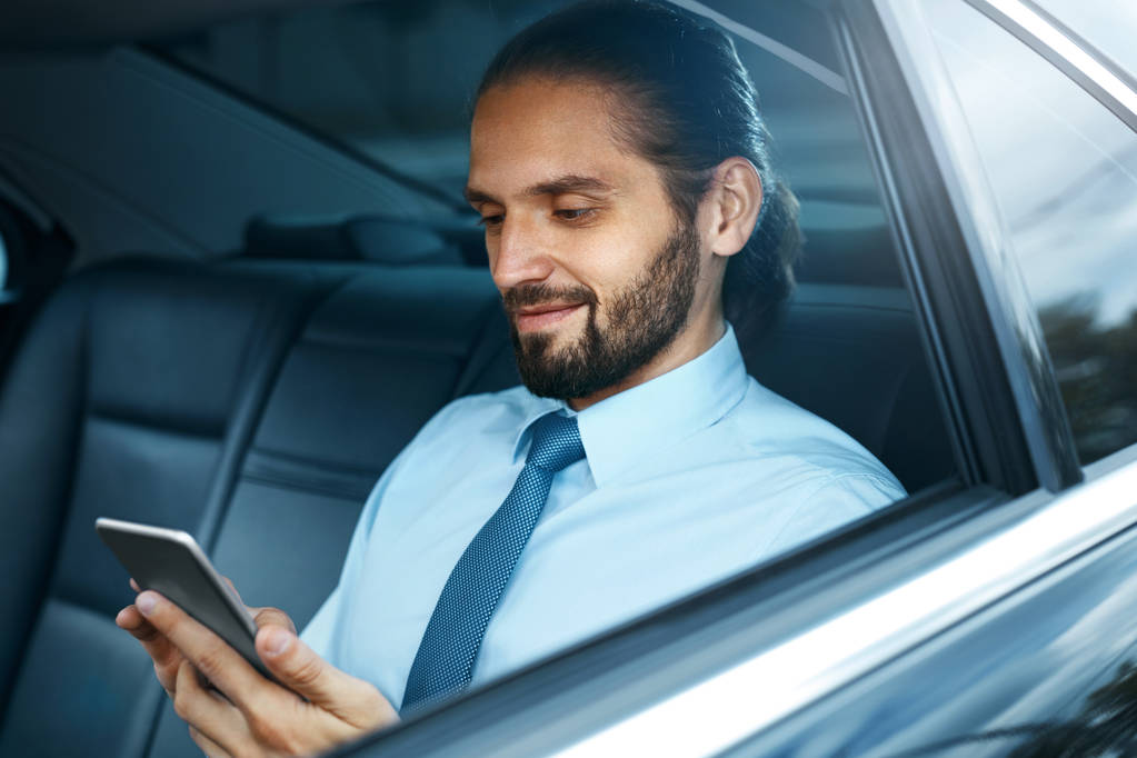 Mladý úspěšný muž pracuje na telefonu sedí v autě. - Fotografie, Obrázek