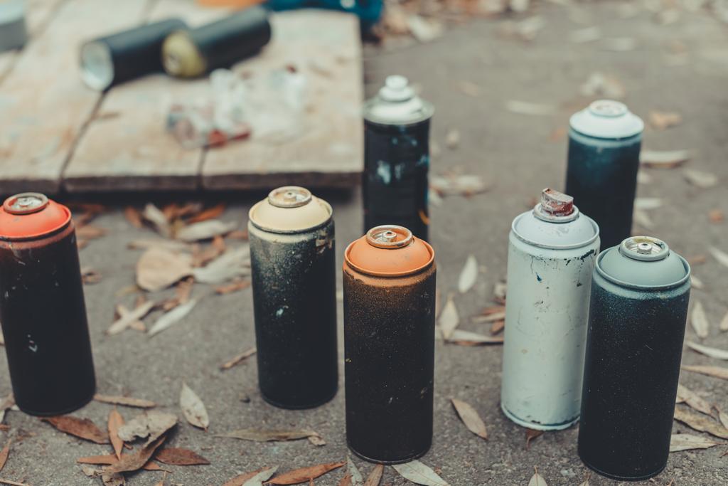 latas con pintura en aerosol de colores para graffiti sobre asfalto
 - Foto, Imagen