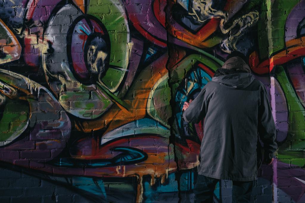 takaisin näkymä katutaiteilijan maalaus graffiti aerosolimaalilla seinään yöllä
 - Valokuva, kuva