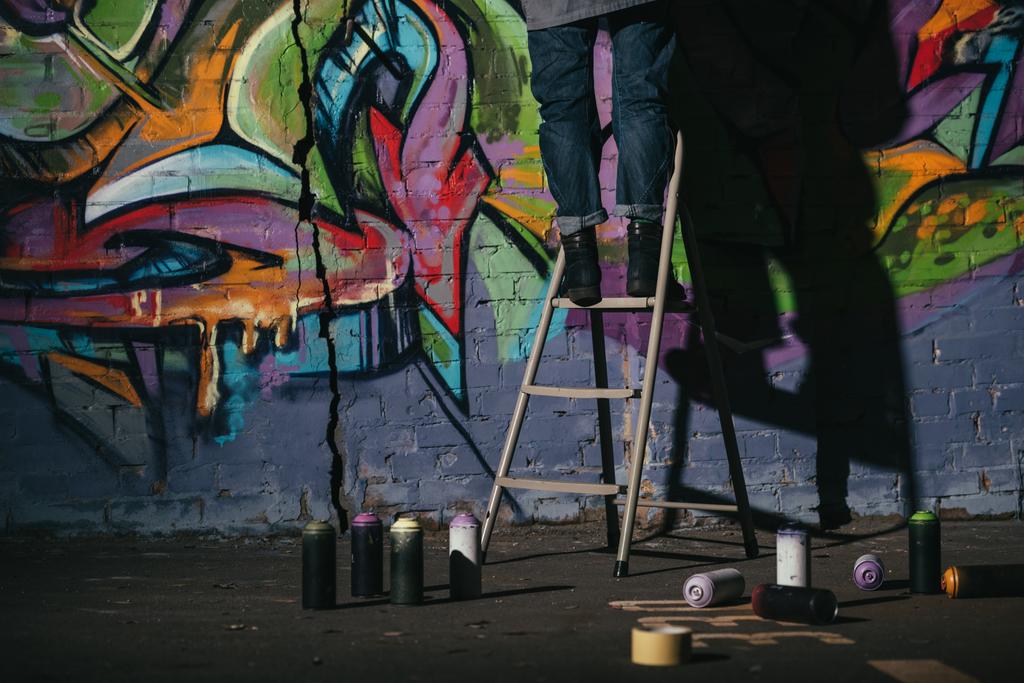 vista cortada de pé na escada e pintura graffiti colorido à noite
 - Foto, Imagem