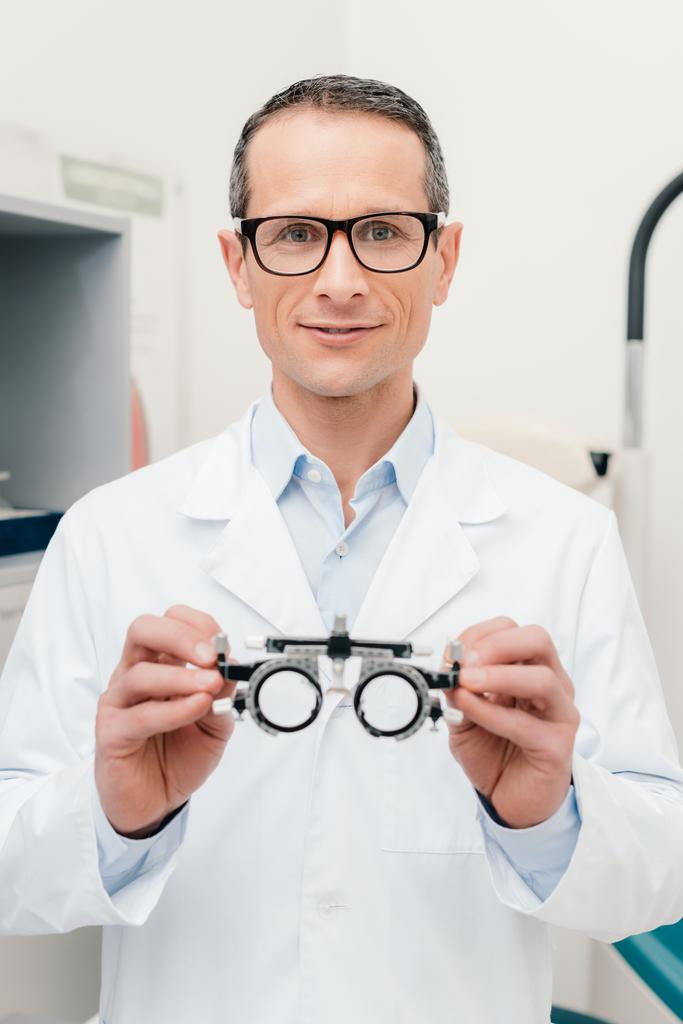 portrait d'optométriste en manteau blanc tenant le cadre du procès dans les mains en clinique
 - Photo, image