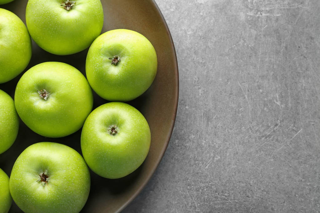 Piatto con mele verdi fresche su sfondo grigio
 - Foto, immagini