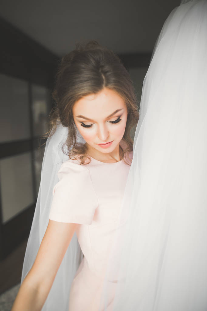 Krásná nevěsta nosí módní svatební šaty s peřím s luxusním make-up a účes, studio focení uvnitř - Fotografie, Obrázek
