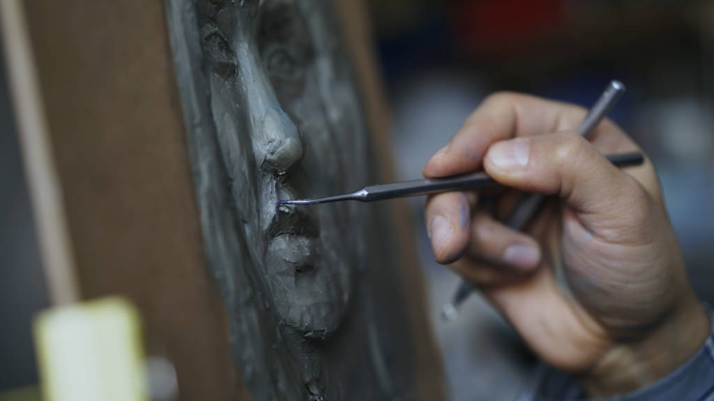 Close-up of Sculptor creating sculpture of humans face on canvas in art studio - Photo, Image
