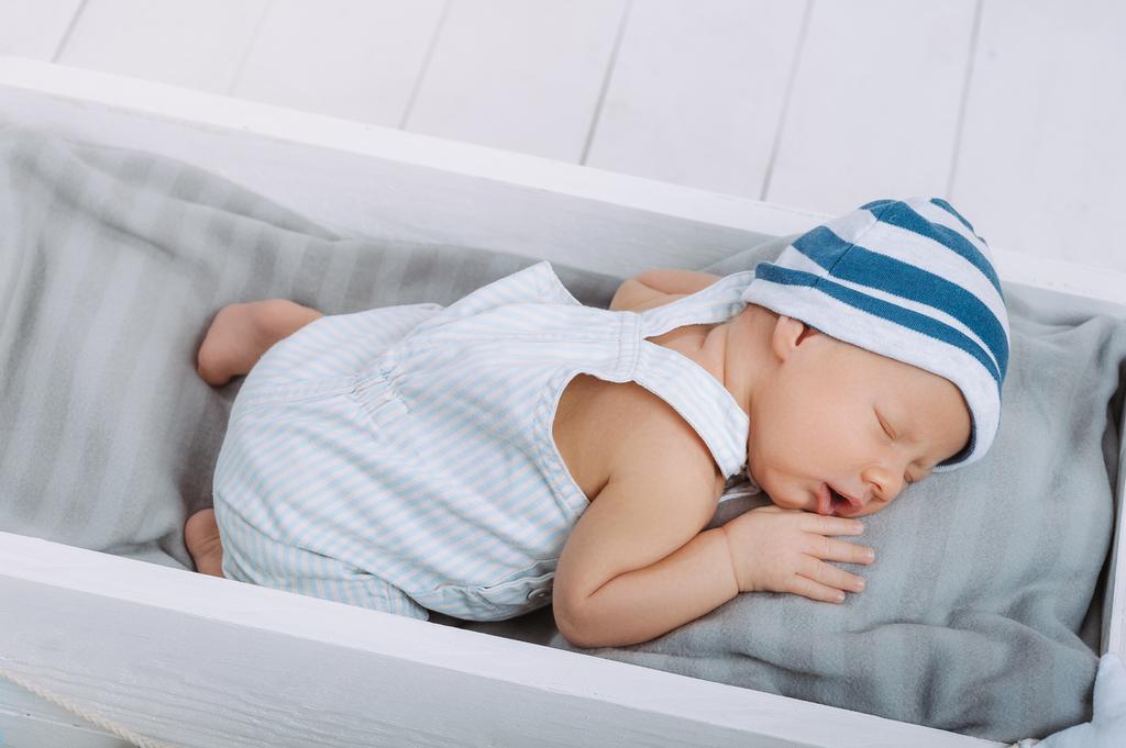 high angle view of cute newborn baby sleeping in wooden baby crib - Photo, Image