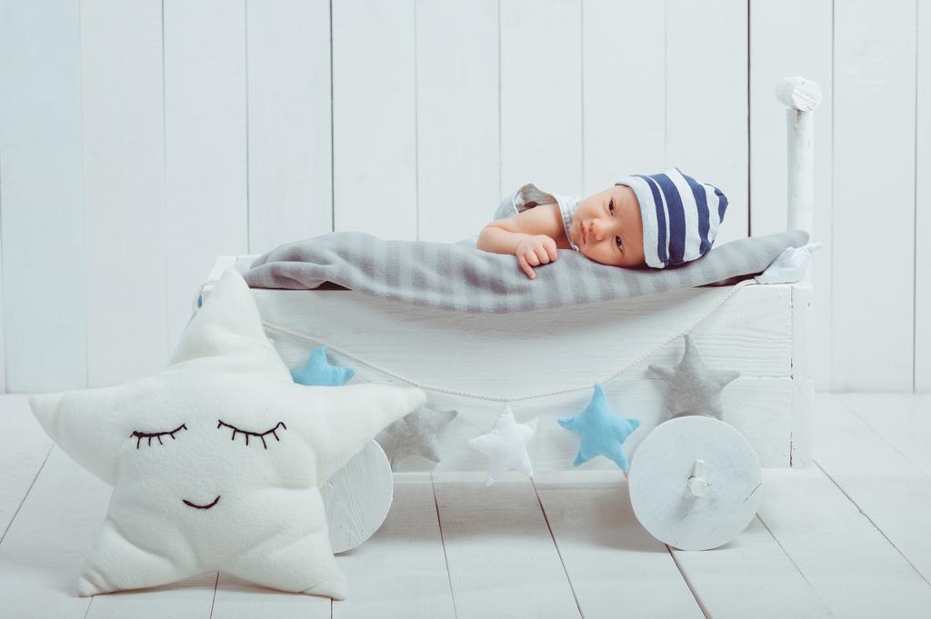 viaton pikkulapsi makaa puisessa vauvansängyssä
 - Valokuva, kuva