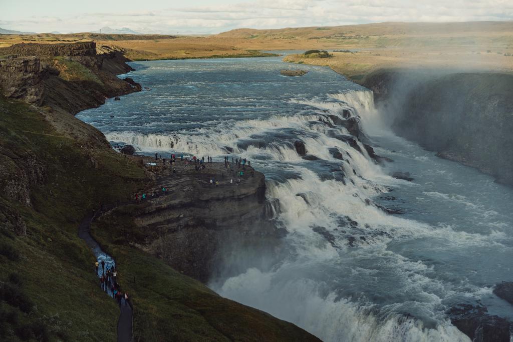 Skupina turistů při pohledu na majestátní vodopád na Islandu  - Fotografie, Obrázek