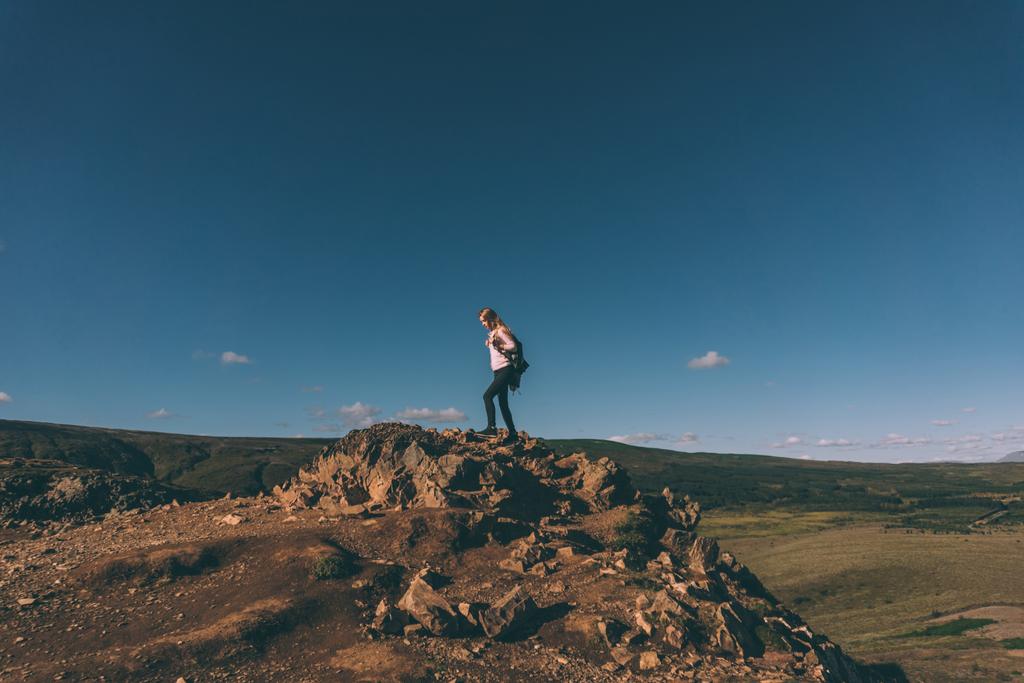 νεαρή γυναίκα στέκεται πάνω σε βράχο και το όμορφο τοπίο της Ισλανδίας  - Φωτογραφία, εικόνα