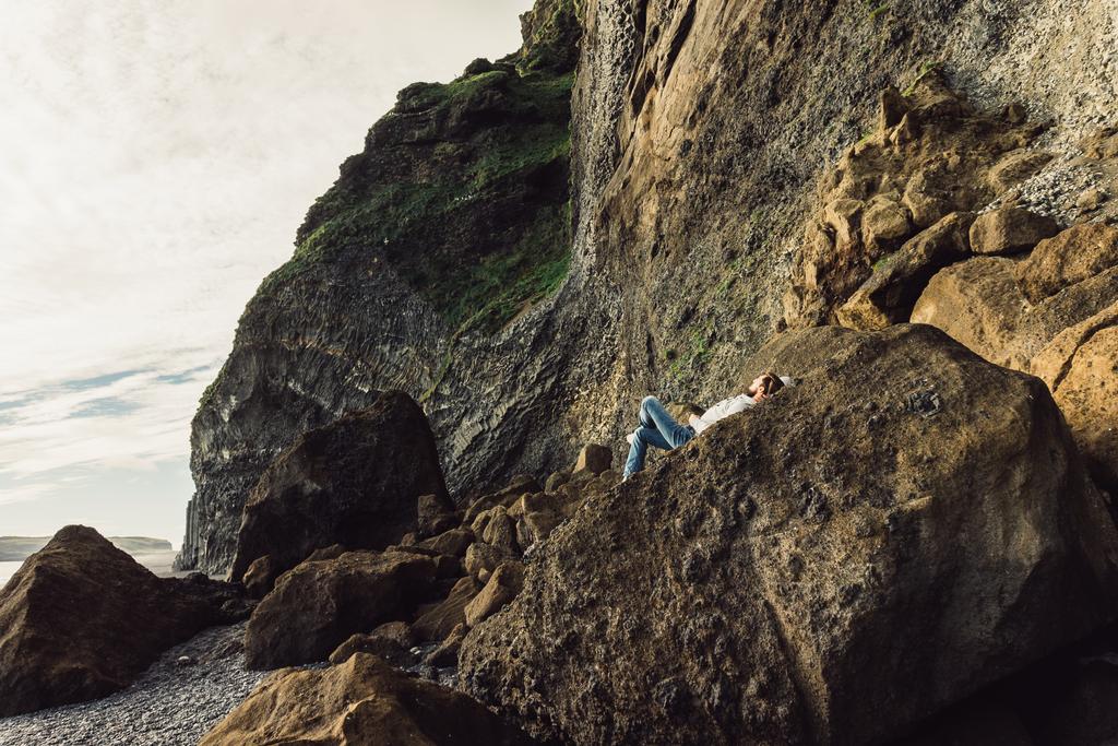 junger Mann liegt auf Klippe und genießt majestätische isländische Landschaft - Foto, Bild