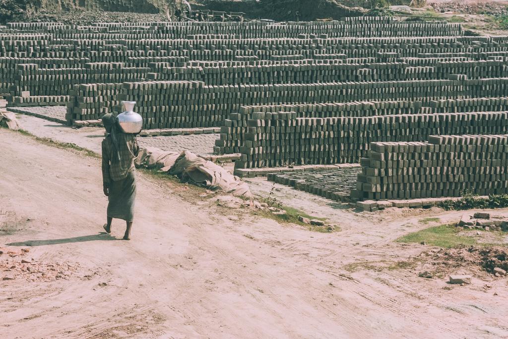 pobre pessoa descalça carregando jarro no ombro e armazém ao ar livre de tijolos ao redor no Nepal
 - Foto, Imagem
