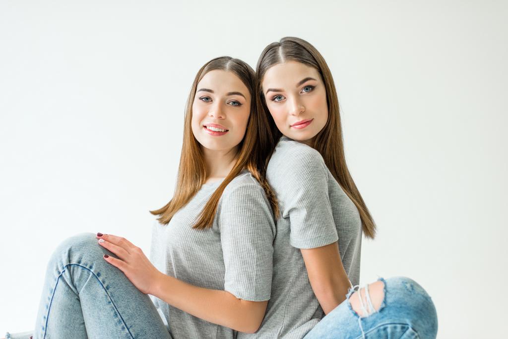 πορτρέτο του ελκυστική δίδυμες αδελφές σε γκρι tshirts συνεδρίαση στην πίσω - Φωτογραφία, εικόνα