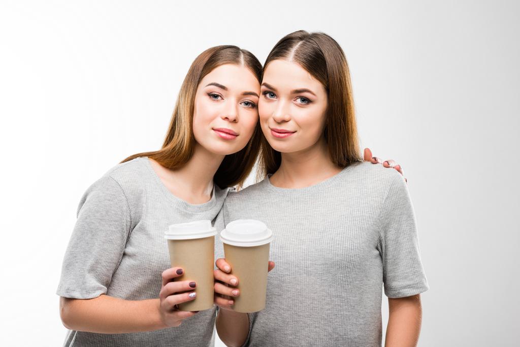 portrét krásné dvojčata s kávou v rukou při pohledu na fotoaparát - Fotografie, Obrázek