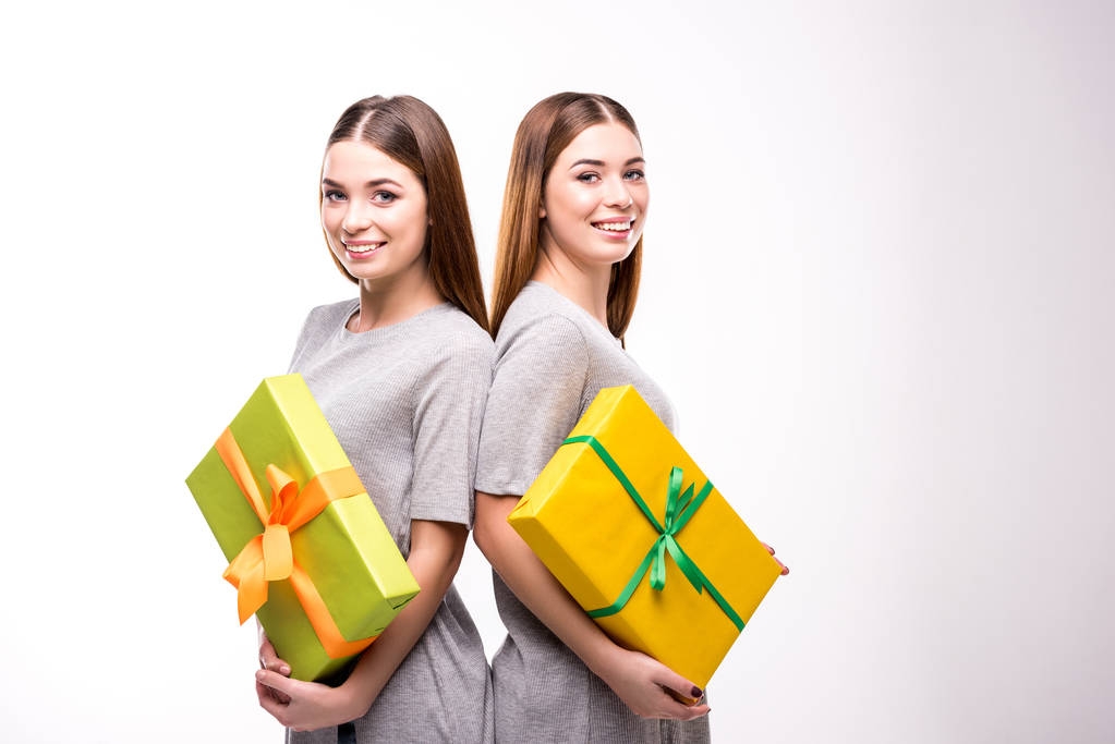portrait of smiling twins with wrapped gifts in hands looking at camera - Photo, Image