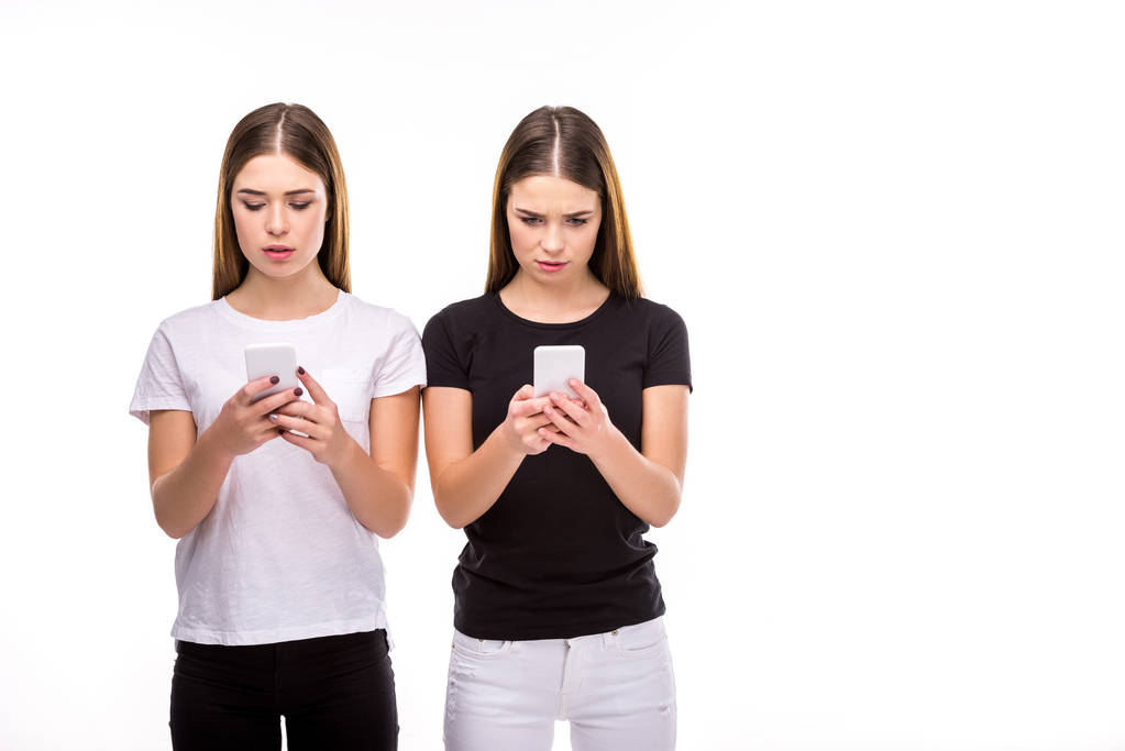 retrato de gemelos hermosos con teléfonos inteligentes aislados en blanco
 - Foto, imagen