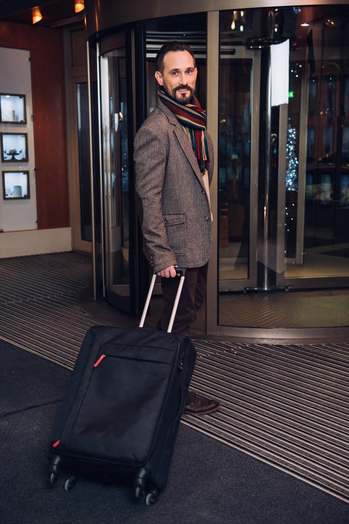 przystojny środku wieku człowieka z walizką, wprowadzając nowoczesne hotel - Zdjęcie, obraz