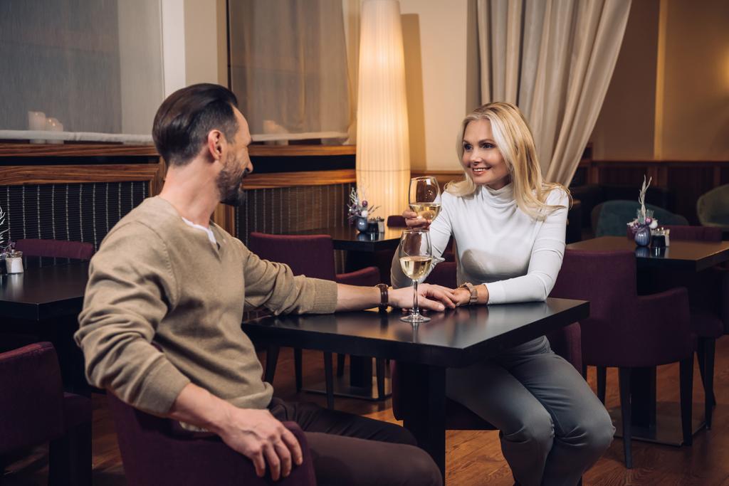 kaunis keski-ikäinen pari juo viiniä ja hymyilevät toisilleen hotellin ravintolassa
    - Valokuva, kuva