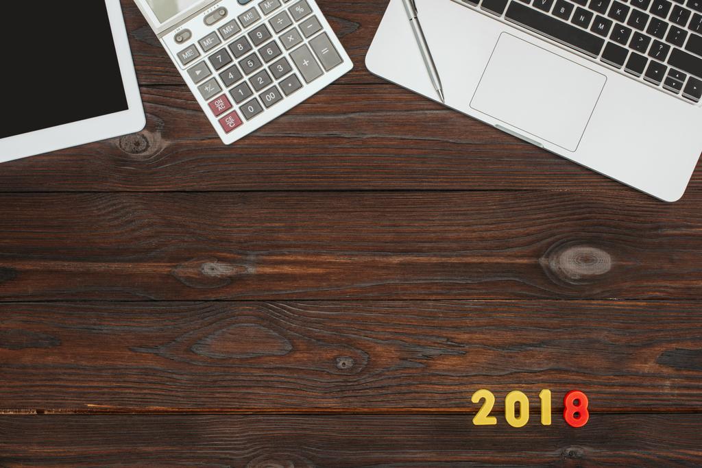Widok z góry z laptopa, tabletu, kalkulator i 2018 numery na drewnianym blatem - Zdjęcie, obraz
