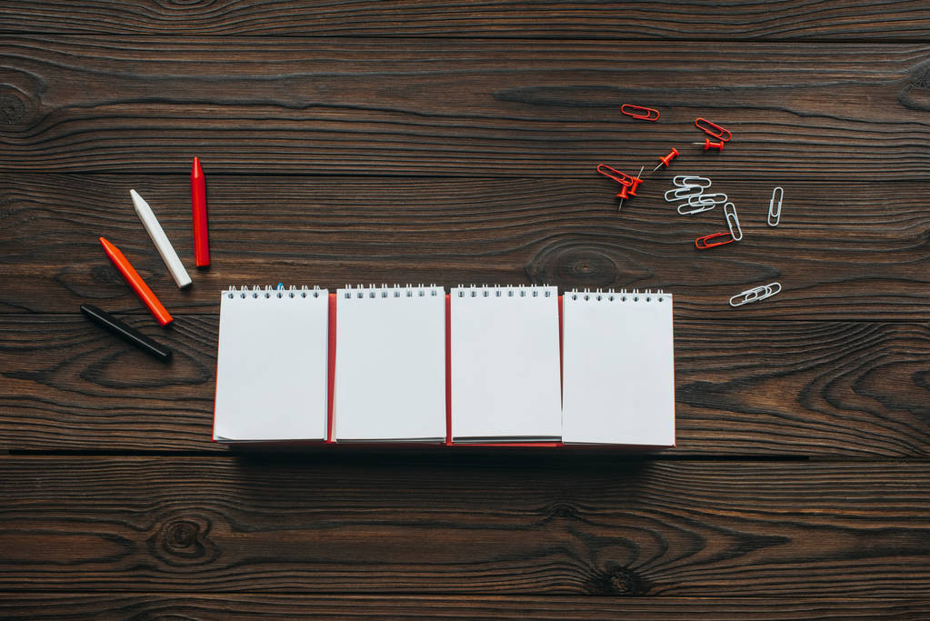 bovenaanzicht van gearrangeerde lege kalender, potloden, clips en pennen op houten tafelblad - Foto, afbeelding
