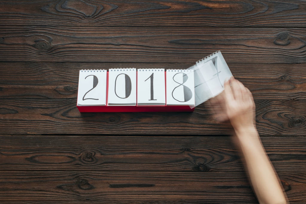 recortado tiro de mujer rasgando papel calendario de 2018 año con superficie de madera oscura como fondo
 - Foto, imagen