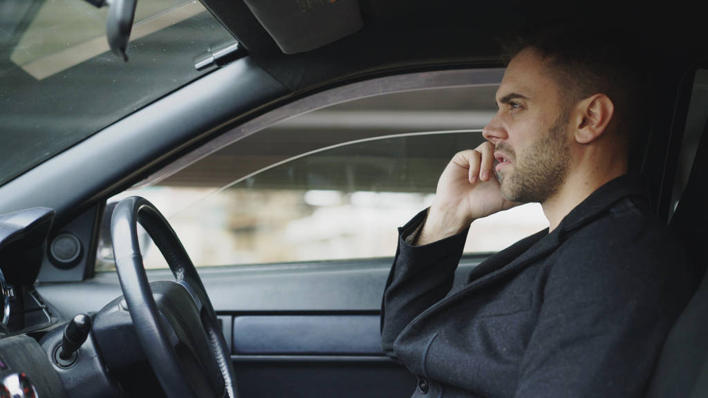 Empresário estressado jurando e falando telefone enquanto sentado dentro do carro ao ar livre
 - Foto, Imagem