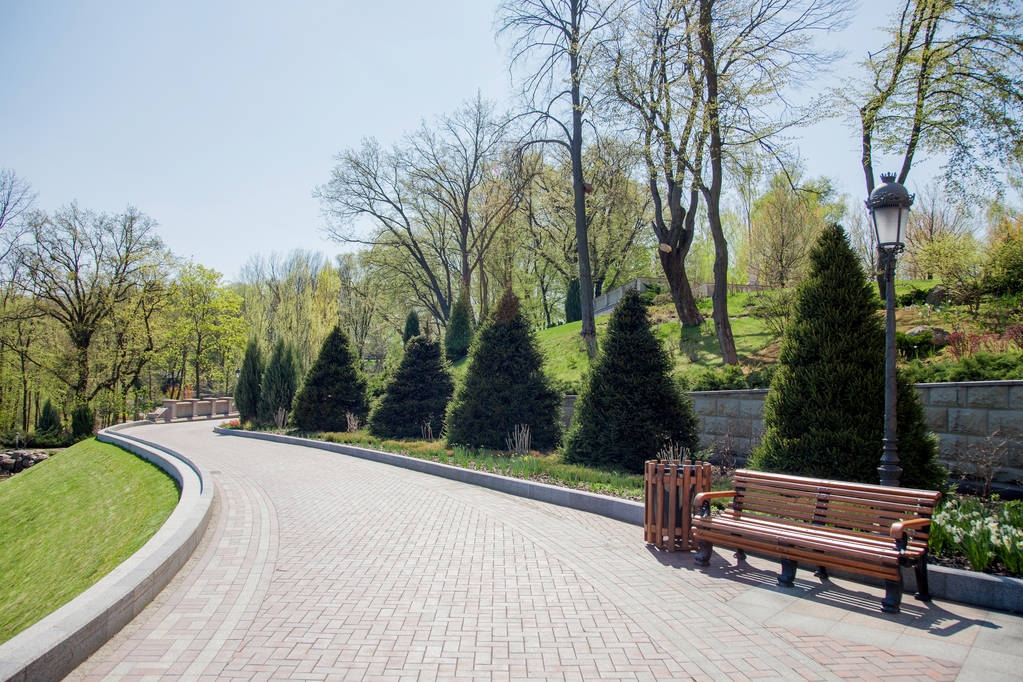 Belle scène de parc dans un parc public avec pelouse verte, sentiers et bancs en pierre, arbres verts, aménagement paysager
 - Photo, image