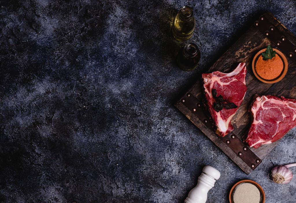 Ansicht von rohem Fleisch auf Holzschneidebrett mit Gewürzen - Foto, Bild