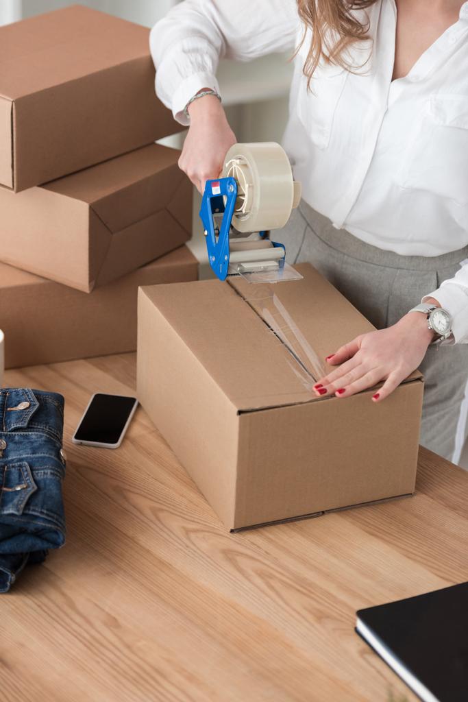 partial view of entrepreneur packing customers parcel with adhesive tape - Photo, Image