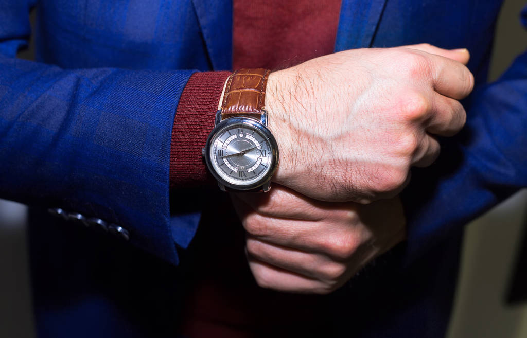 Levensstijl foto van elegante zakenlieden dragen luxe horloge. Succesvolle man. Donker blauwe kostuum en rode wollen trui. - Foto, afbeelding