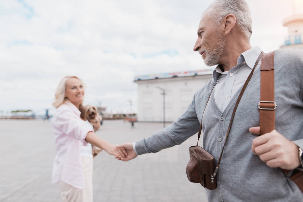 Yaşlı bir çift meydanın yürüyor. Bir kadın bir adam elinden tutar ve yol açar - Fotoğraf, Görsel