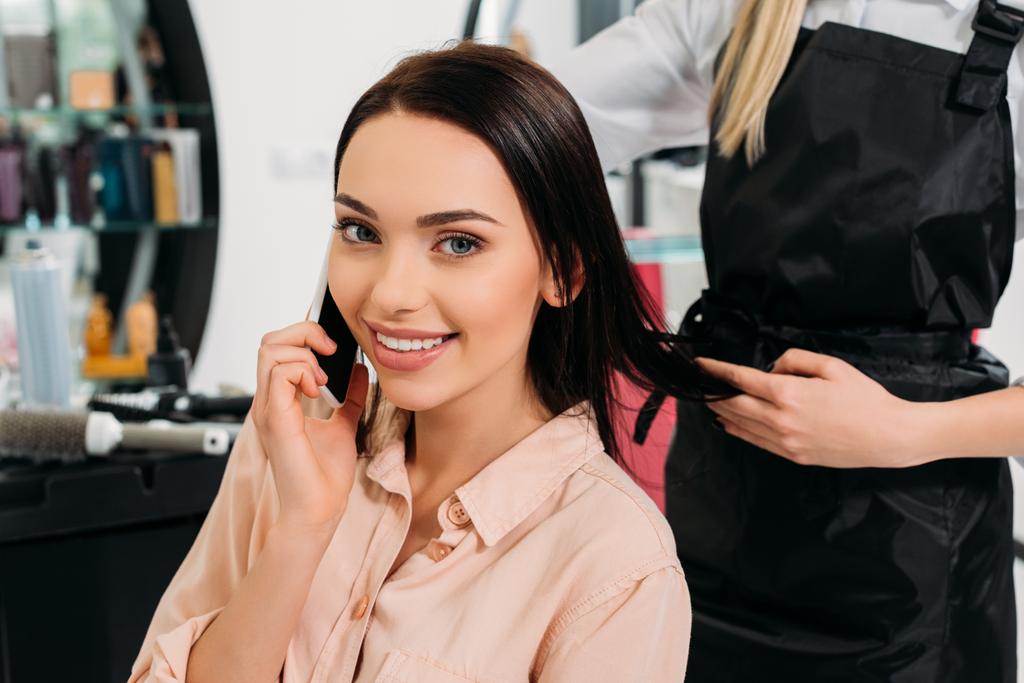 cropped image of woman talking by smartphone at hair salon  - Photo, Image