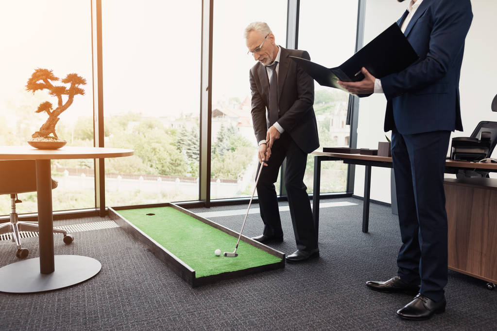 Der Mitarbeiter kam mit einem Bericht zum Direktor. Direktor spielt Golf im Büro - Foto, Bild