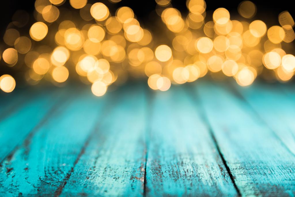 festliche Bokeh-Lichter auf blauer Holzoberfläche, weihnachtlicher Hintergrund - Foto, Bild
