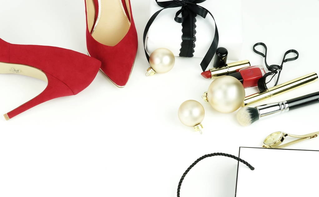 Accesorios femeninos de moda: zapatos rojos de tacón alto, regalo, cosméticos, paquete, accesorios y bolas de Navidad sobre un fondo blanco. Copiar espacio
 - Foto, Imagen