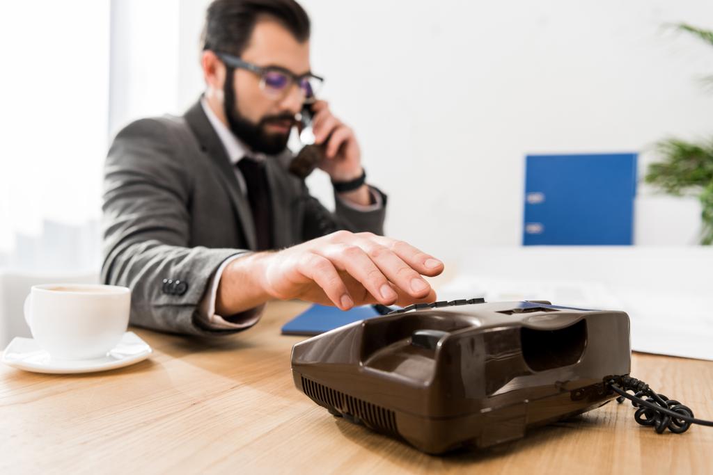 бізнесмен набирає номер зі стаціонарним телефоном в офісі
 - Фото, зображення