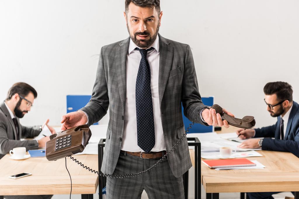 бізнесмен стоїть зі стаціонарним телефоном в офісі
 - Фото, зображення