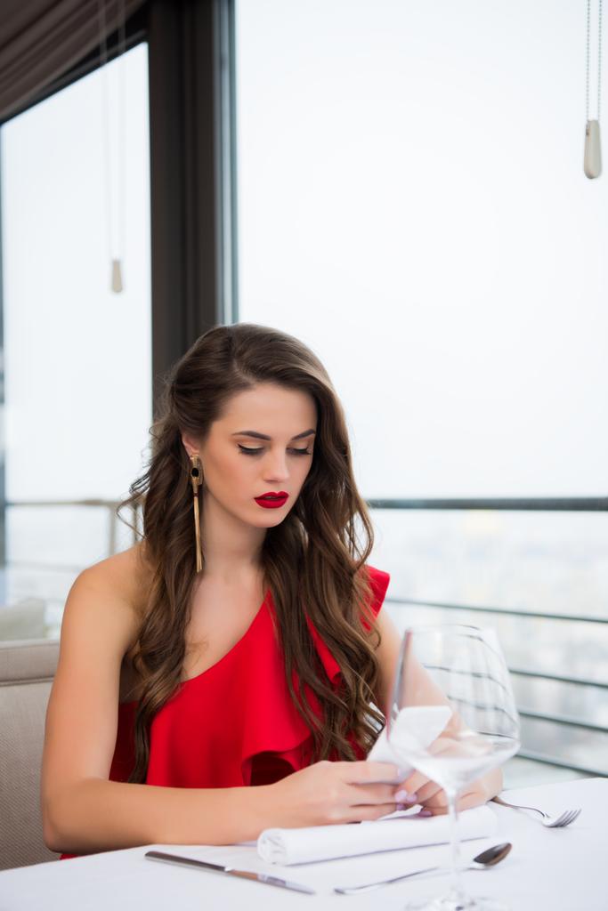 Porträt einer nachdenklichen schönen Frau, die ihr Smartphone benutzt, während sie im Restaurant auf ihren Freund wartet - Foto, Bild