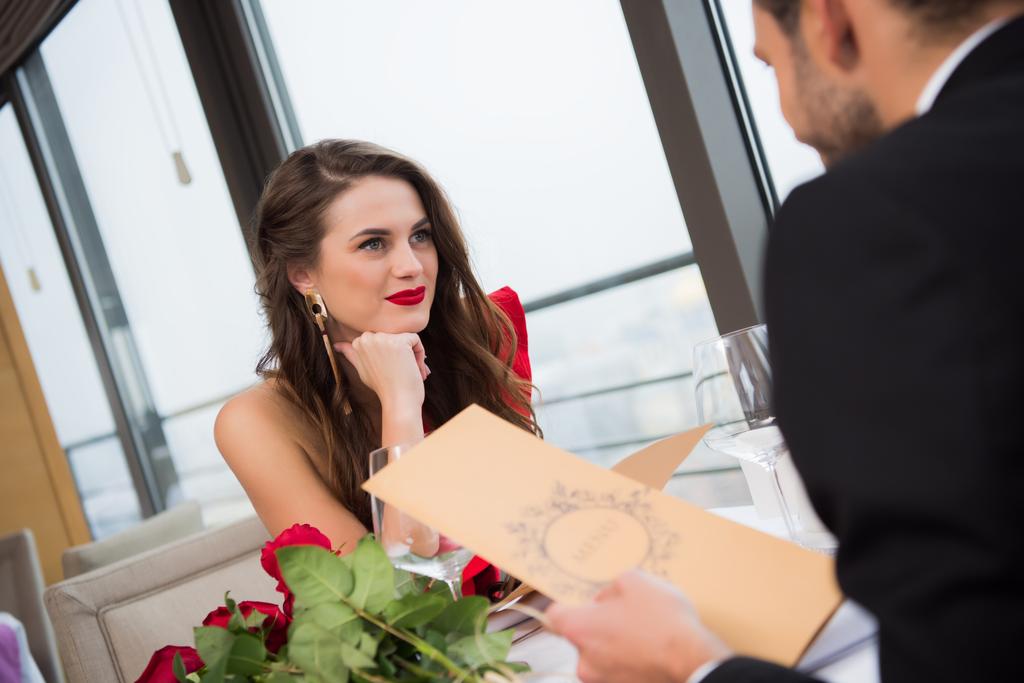 Lachende vrouw kijken vriendje tijdens st valentine dag datum in restaurant - Foto, afbeelding